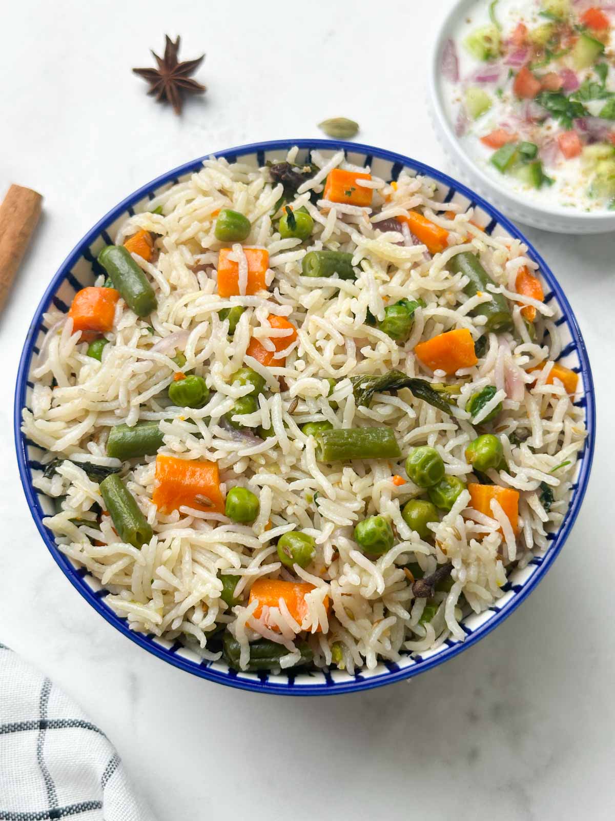 instant pot vegetable pulao served in a bowl with raita on the side