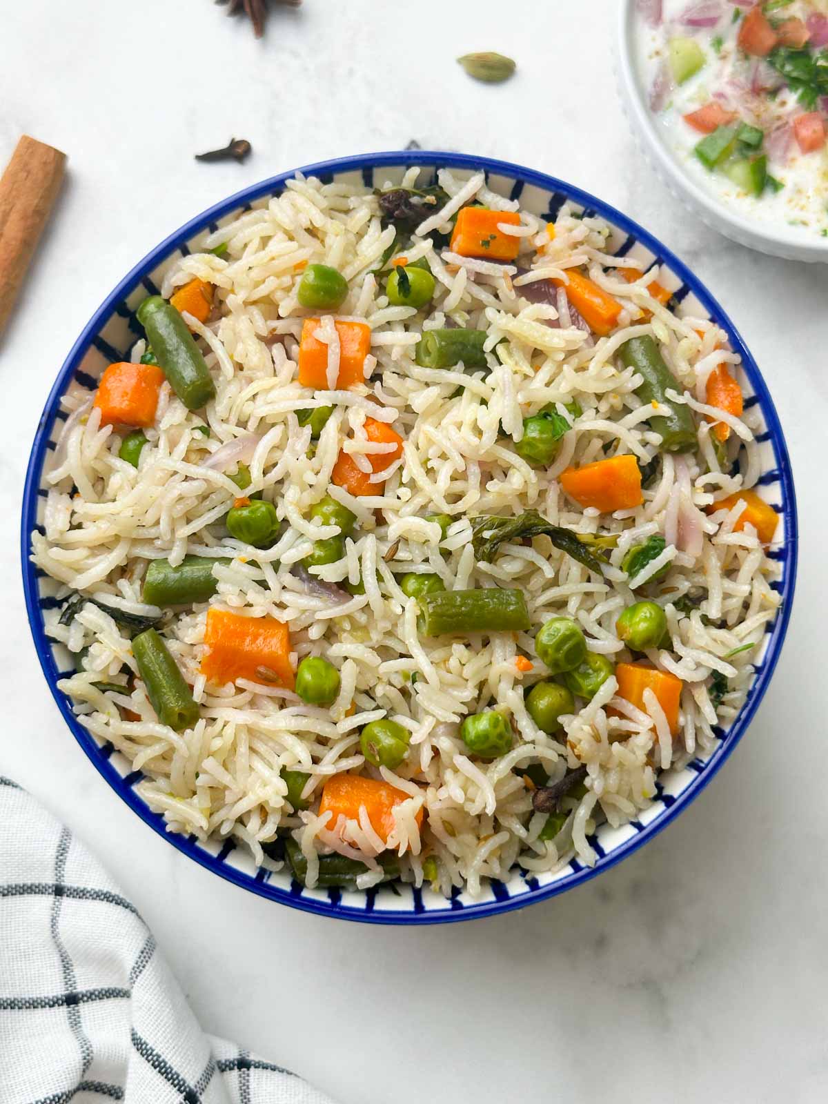 instant pot vegetable pulao served in a bowl with raita on the side