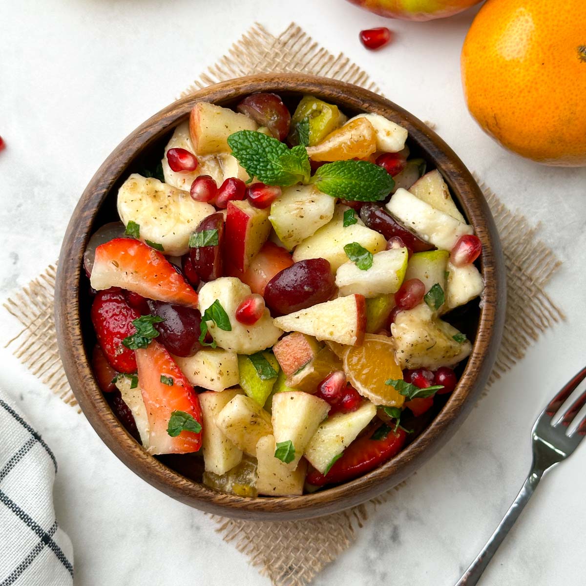 fruit chaat served in a wooden bowl with fruits in the side