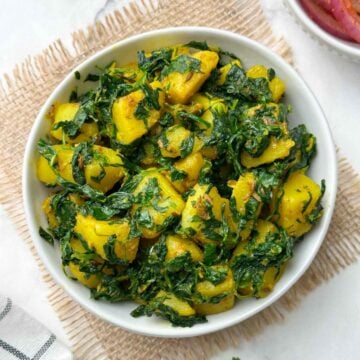aloo methi sabji served in a bowl with onion salad on the side