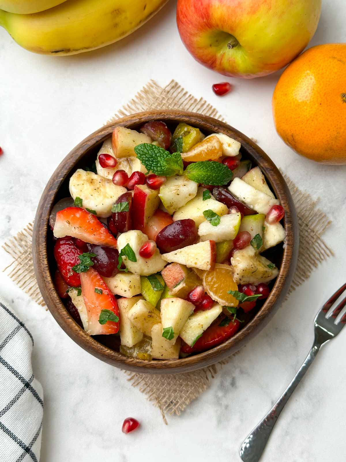 fruit chaat served in a wooden bowl with fruits in the side