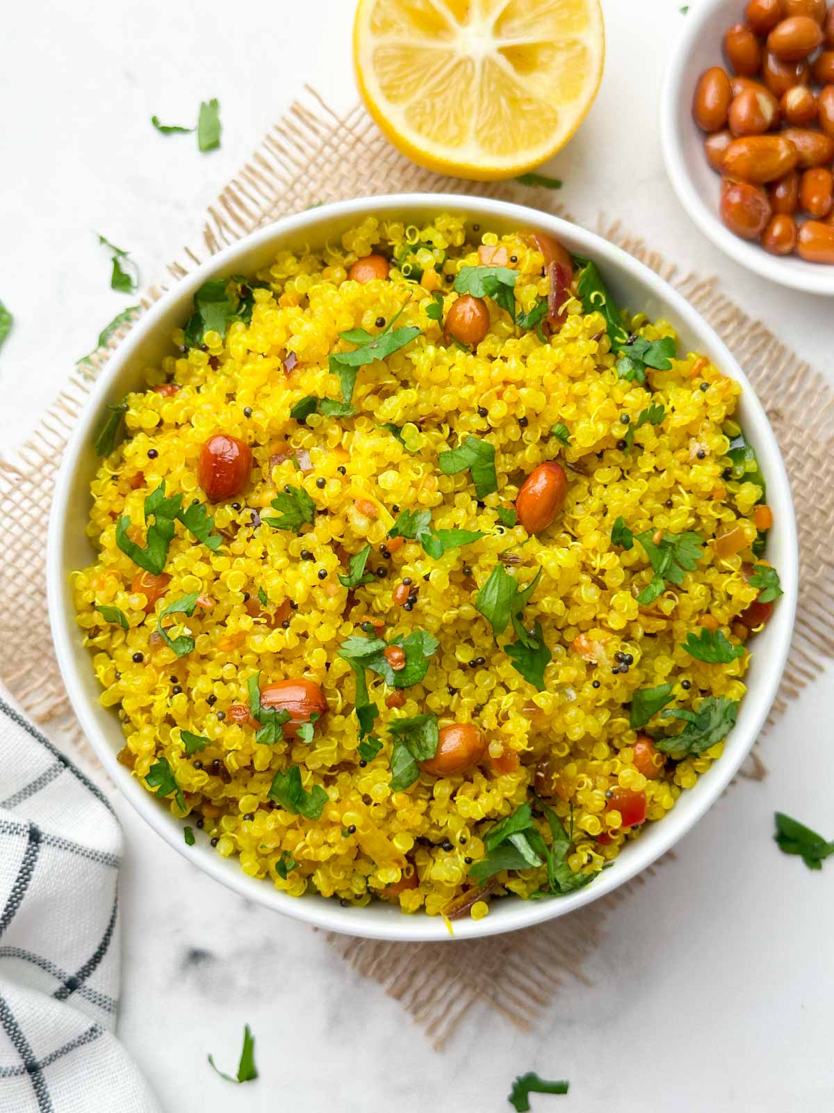 indian lemon quinoa recipe served in a white bowl with lemon and roasted peanuts on the side