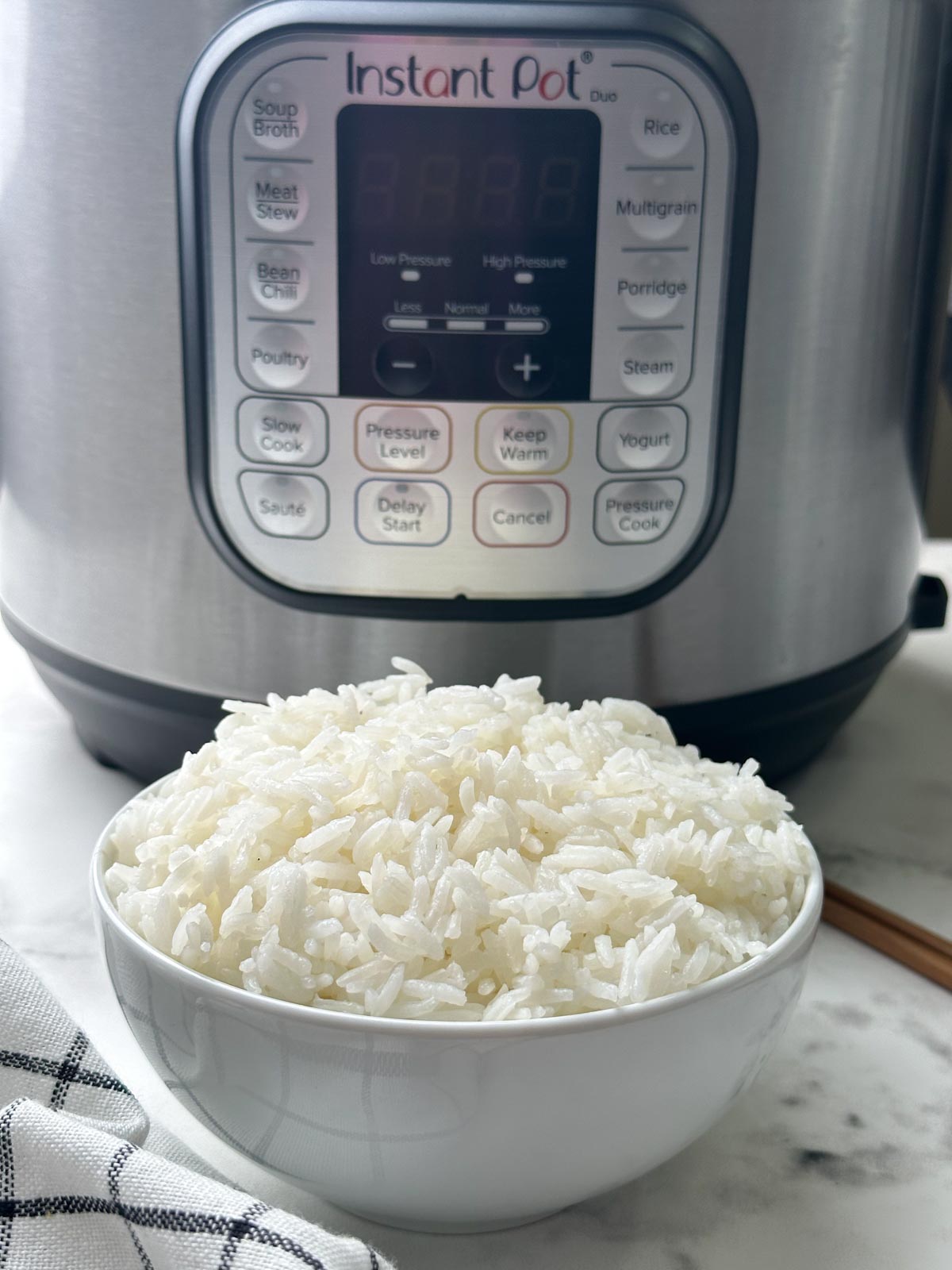 Fluffy jasmine rice in a white bowl and instant pot on the behind