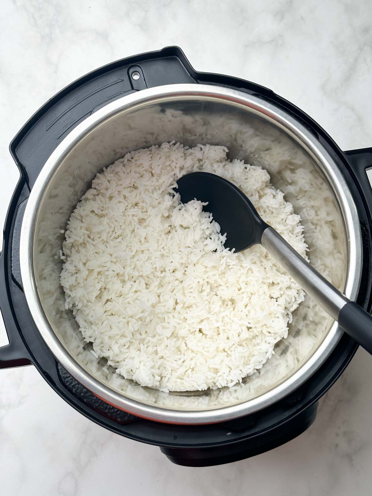 cooked sona masuri rice in the pot with a black spoon