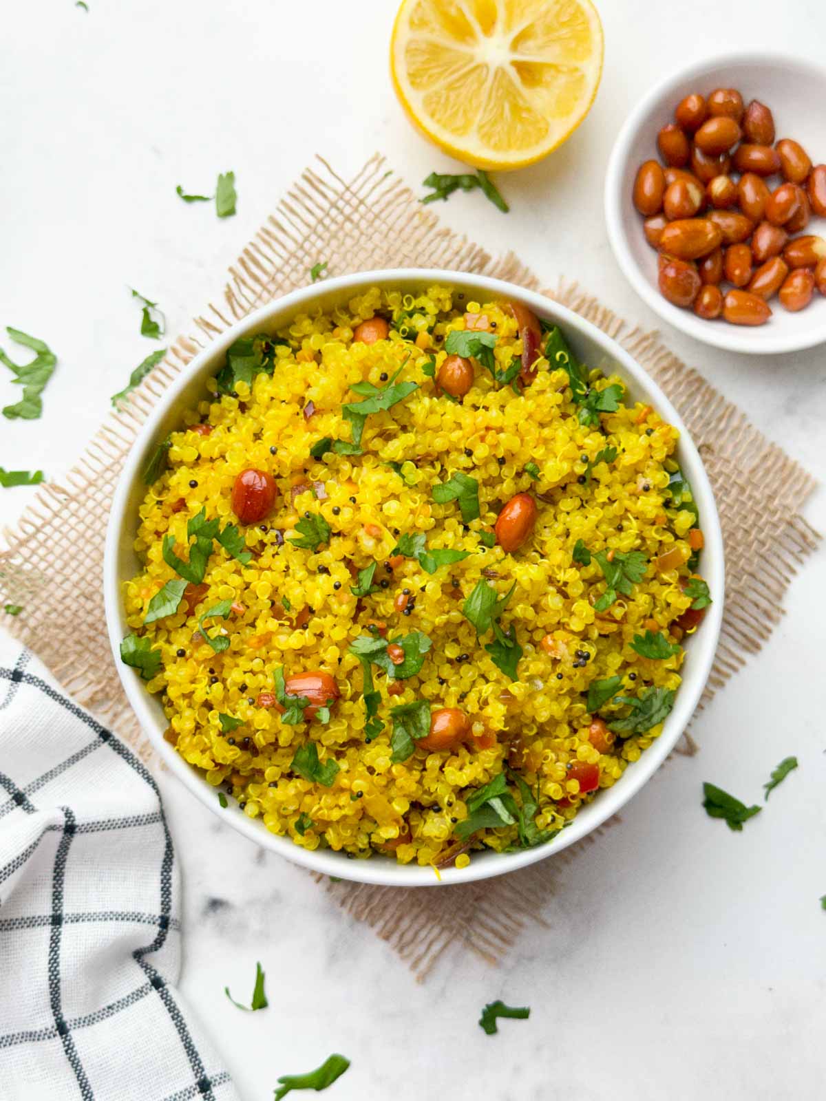 indian lemon quinoa recipe served in a white bowl with lemon and roasted peanuts on the side