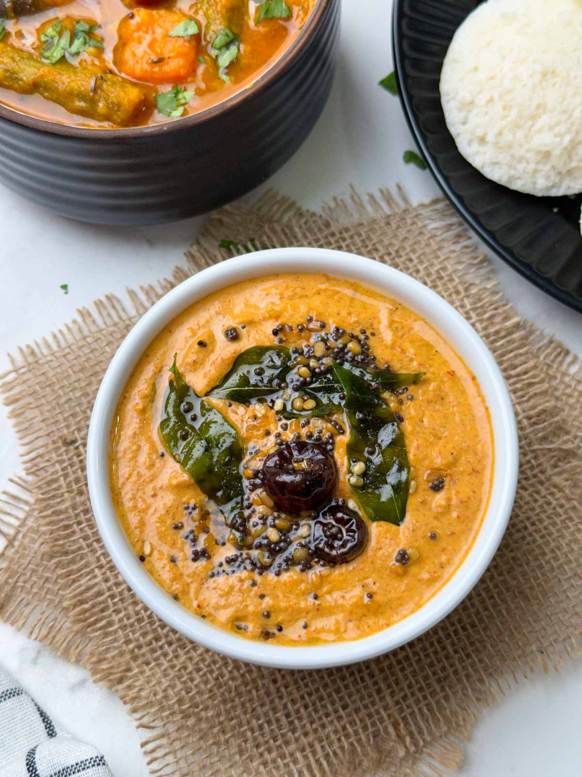 groundnut chutney served in a white bowl with idli and vegetable sambar on the side