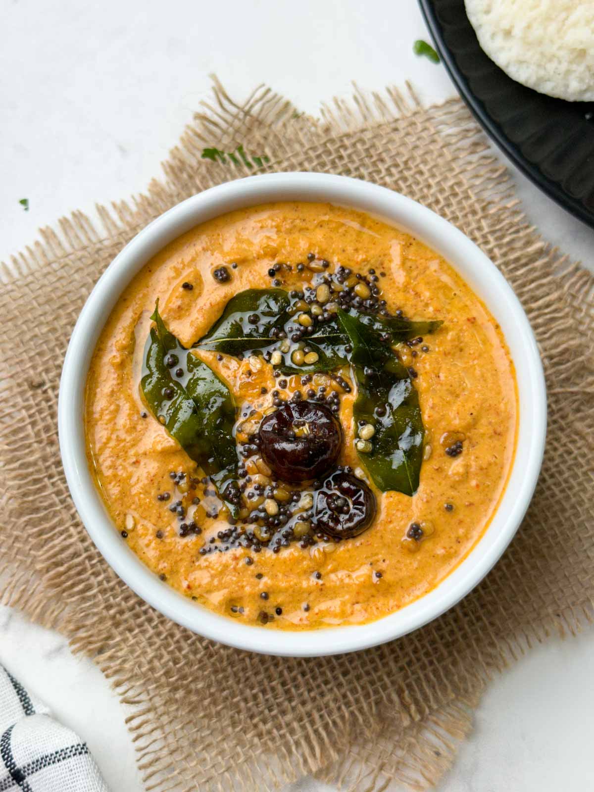 peanut chutney recipe served in a bowl with tempering on the top with idli on the side