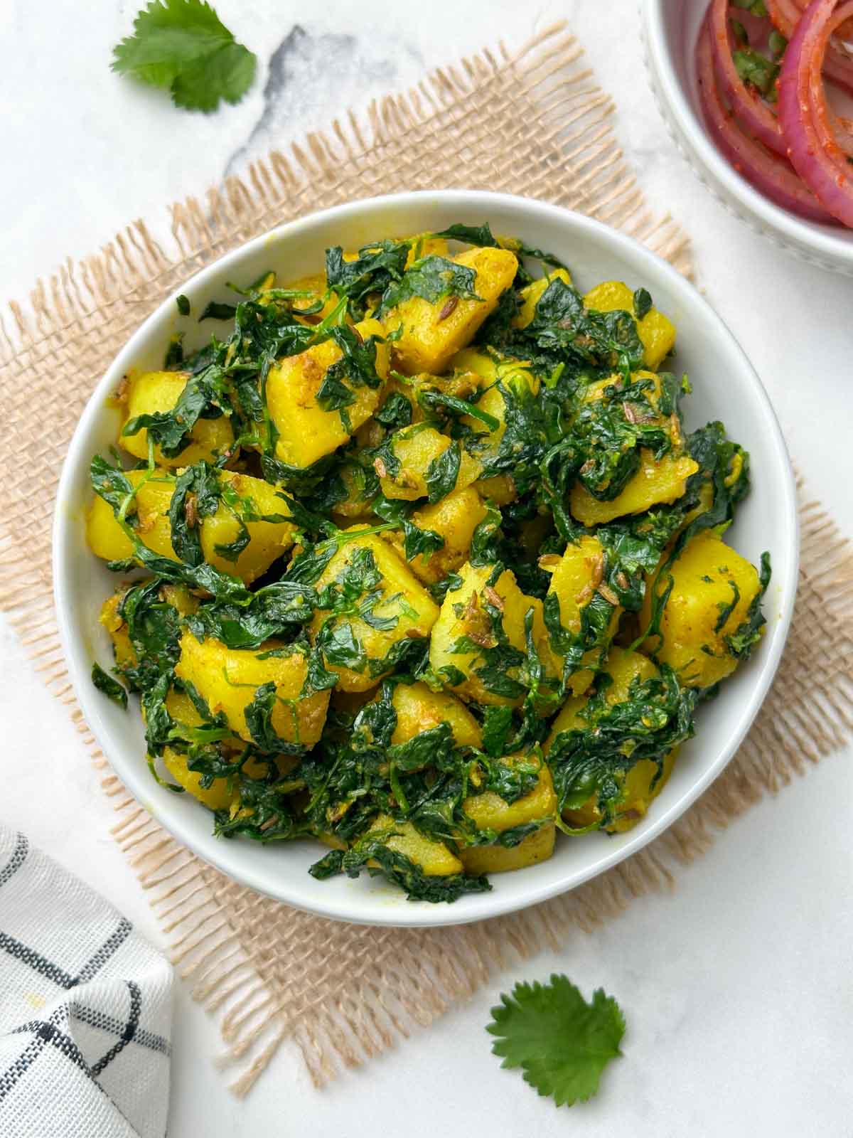 aloo methi sabji served in a bowl with onion salad on the side