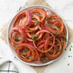 laccha pyaaz (indian onion salad) served on a plate with slice of lemon and green chili on the side