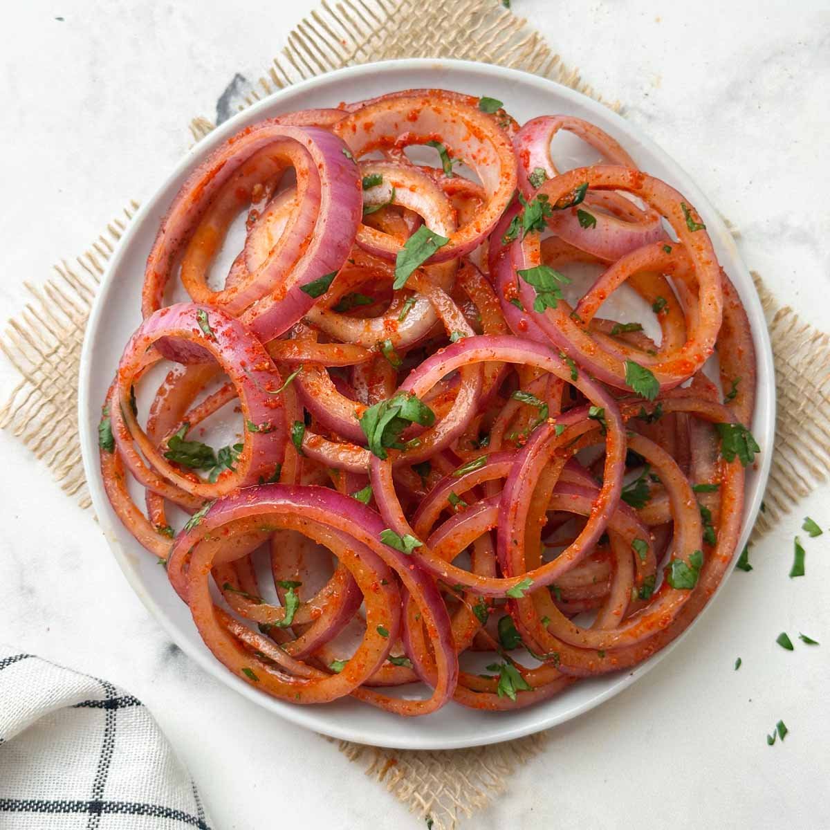 laccha pyaaz (indian onion salad) served on a plate with slice of lemon and green chili on the side