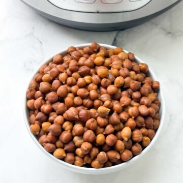 cooked black chickpeas (kala chana) in a bowl with instant pot behind the bowl