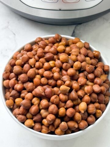 cooked black chickpeas (kala chana) in a bowl with instant pot behind the bowl