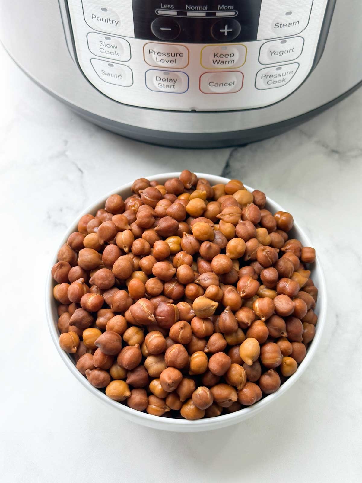 cooked black chickpeas (kala chana) in a bowl with instant pot behind the bowl