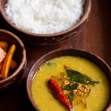 khati dal served in a bowl with rice and carrot pickle on the side.