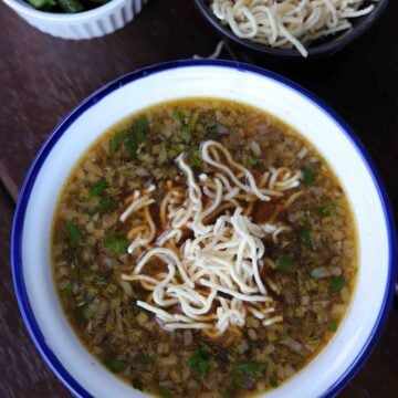 Veg manchow soup served in a soup bowl with vegetables and noodles on the side