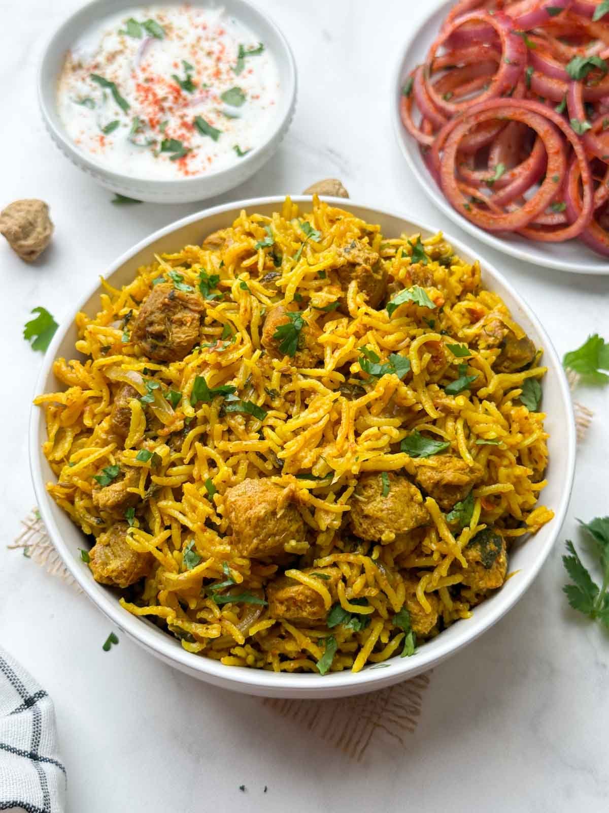 soya chunks biryani (meal maker biryani) served in a bowl with onion salad and raita on the side