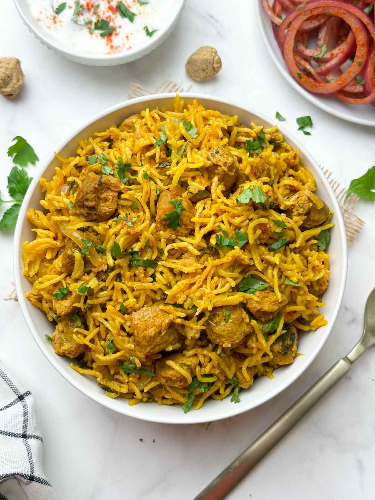 soya chunks biryani (meal maker biryani) served in a bowl with onion salad and raita on the side 