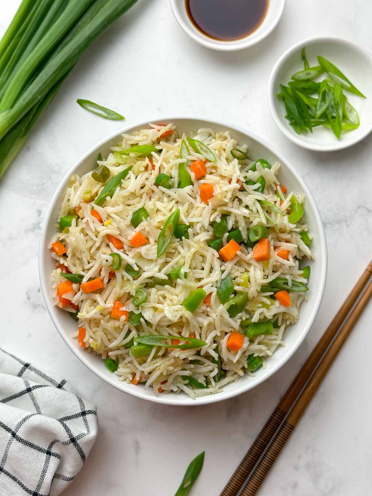 veg fried rice served in a bowl with soy sauce and green onions on the side