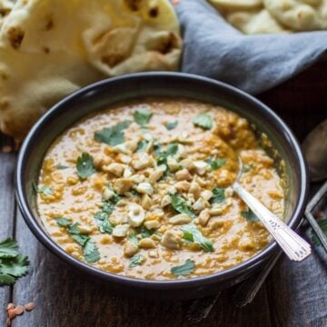 vegetarian indian mulligatawny soup served in a bowl with a spoon and naan on the side
