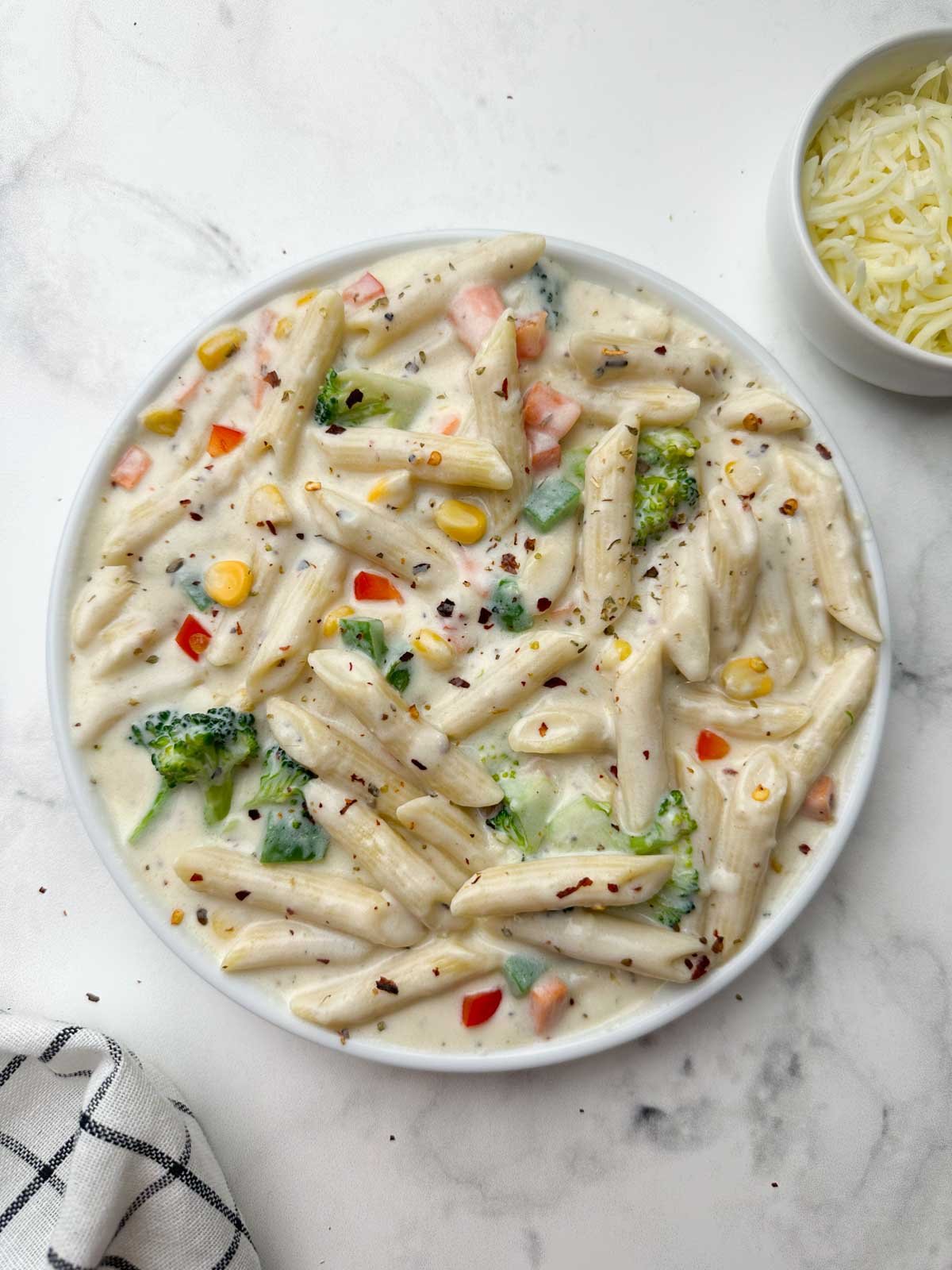 white sauce pasta (bechamel sauce pasta) served in a plate with cheese on the side