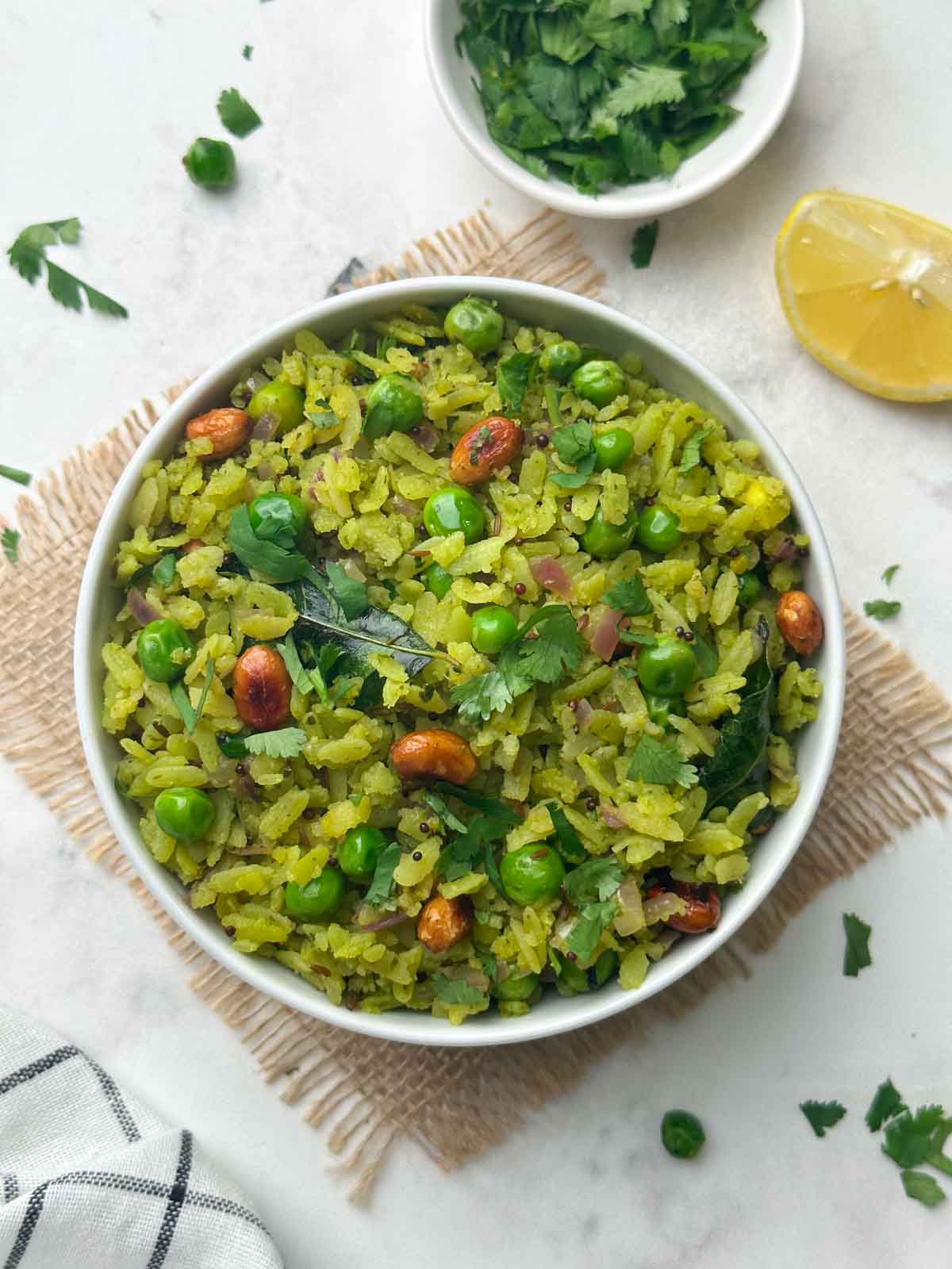hariyali poha served in a bowl with coriander leaves and lemon wedge on the side