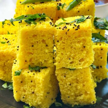 khaman dhokla on a plate with sweet tamarind and green chutney on the side