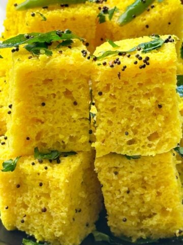 khaman dhokla on a plate with sweet tamarind and green chutney on the side