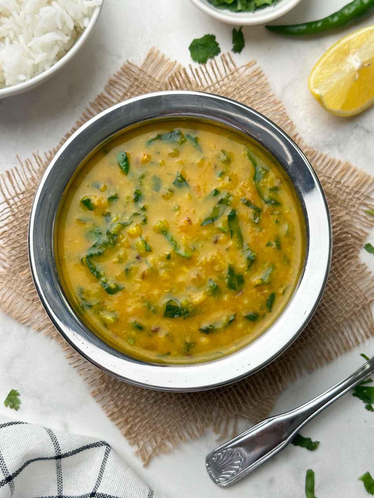 dal palak recipe served in a kadai and rice and lemon wedge on the side
