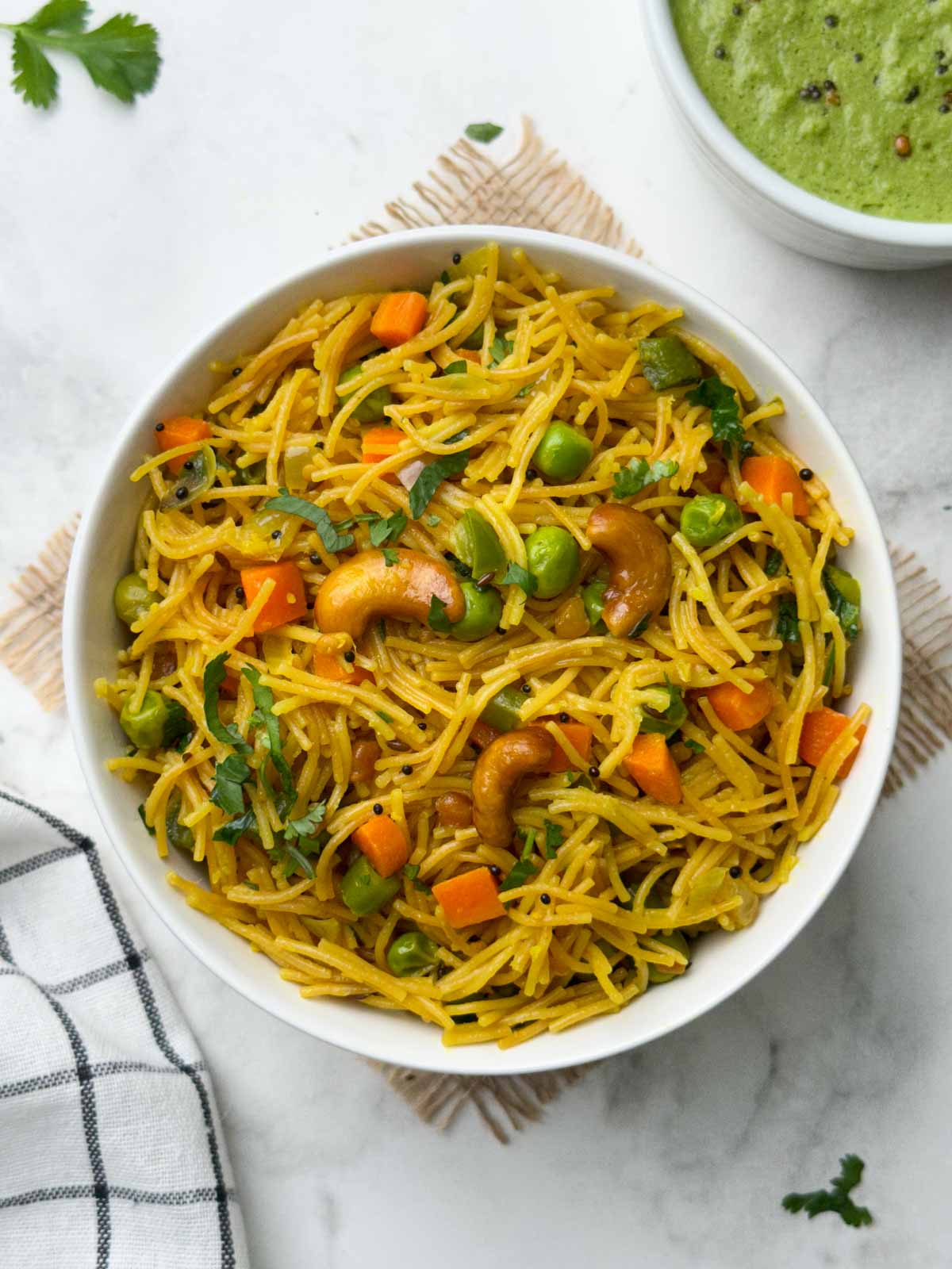 semiya Upma served in a white bowl with a spoon and green coconut chutney on the side