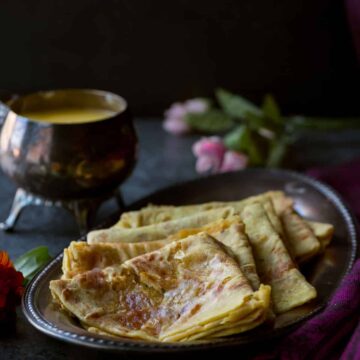 Puranpoli served on a plate with ghee on the side