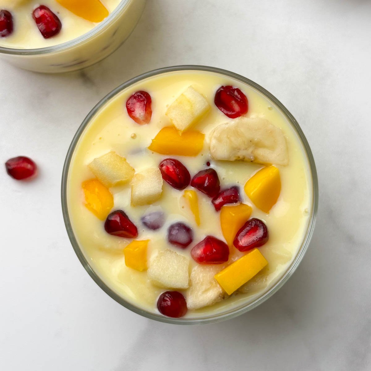 fruit custard served in 2 glass bowls with a spoon