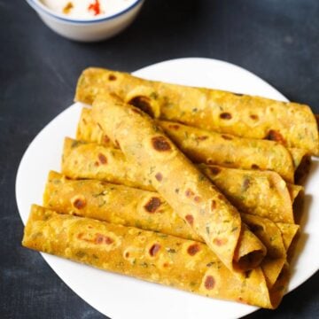 Methi thepla served on a plate with raita on the side