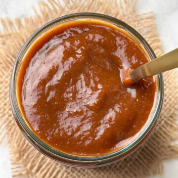 tamarind chutney in a glass jar with a spoon