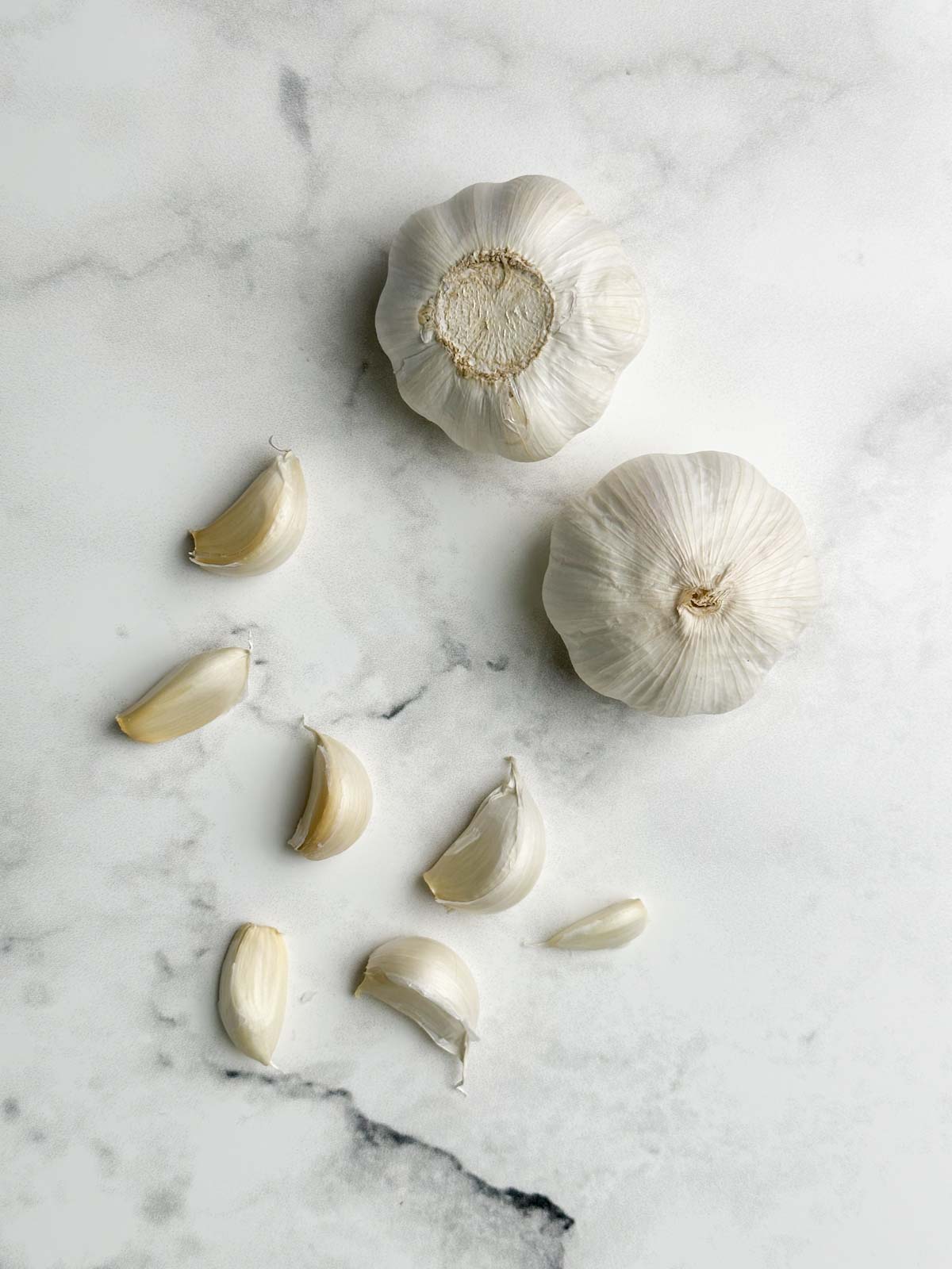 whole garlic and unpeeled cloves on the white sheet