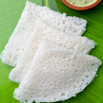 three neer dosa layed on each other with coconut chutney on the side