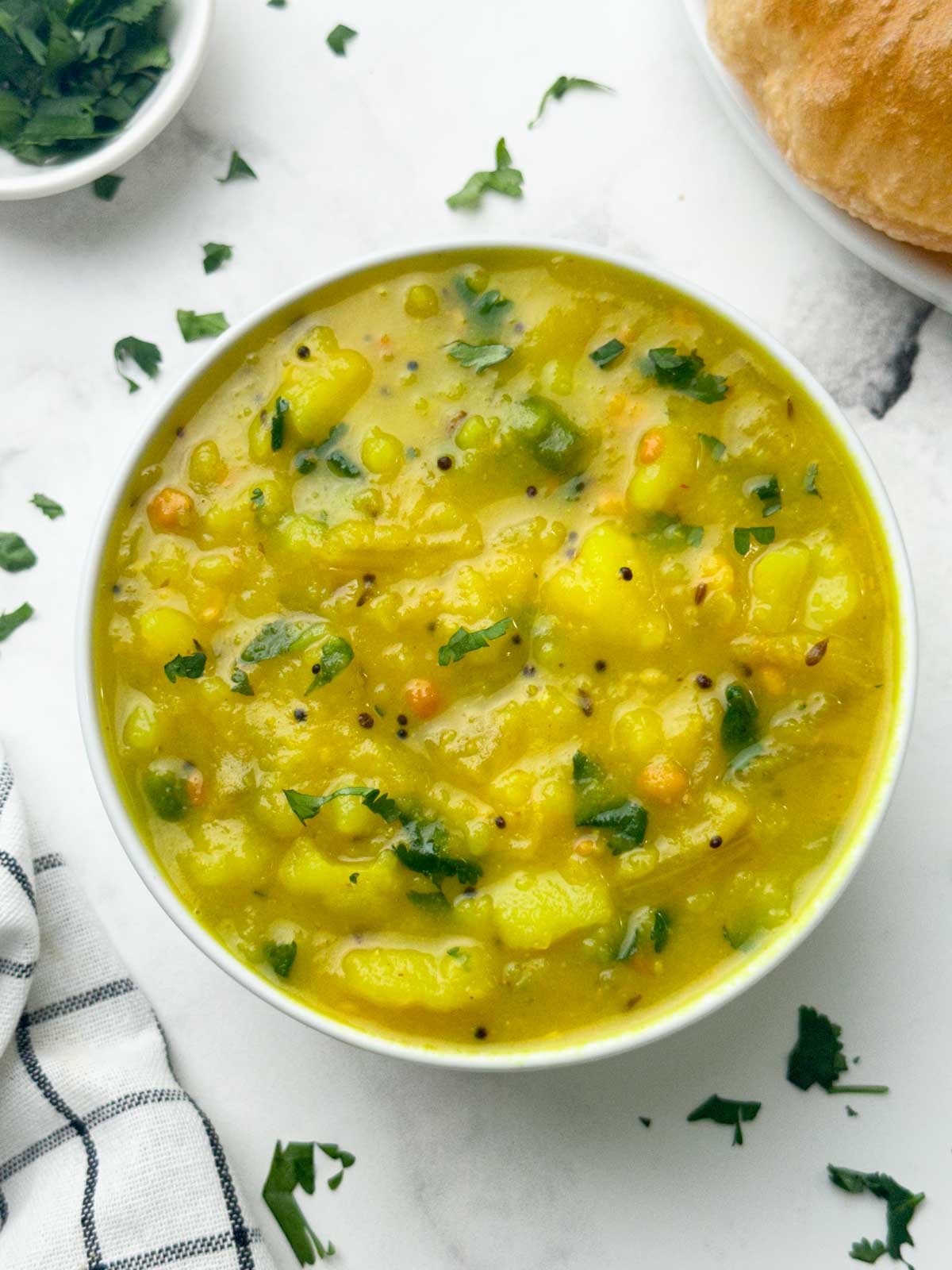 potato sagu served in a bowl with poori on the side