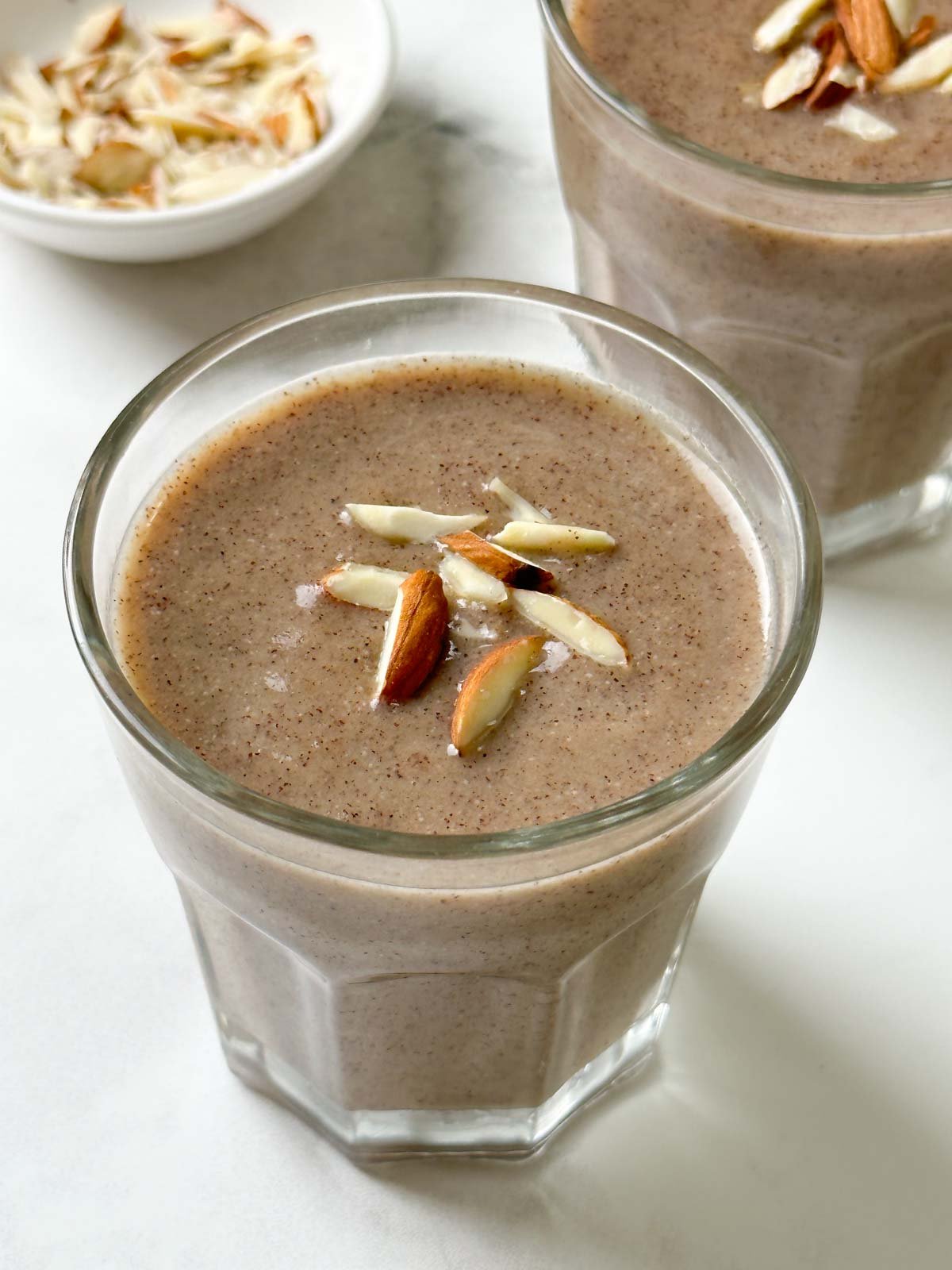 ragi malt served in two glass cups garnished with slivered almonds