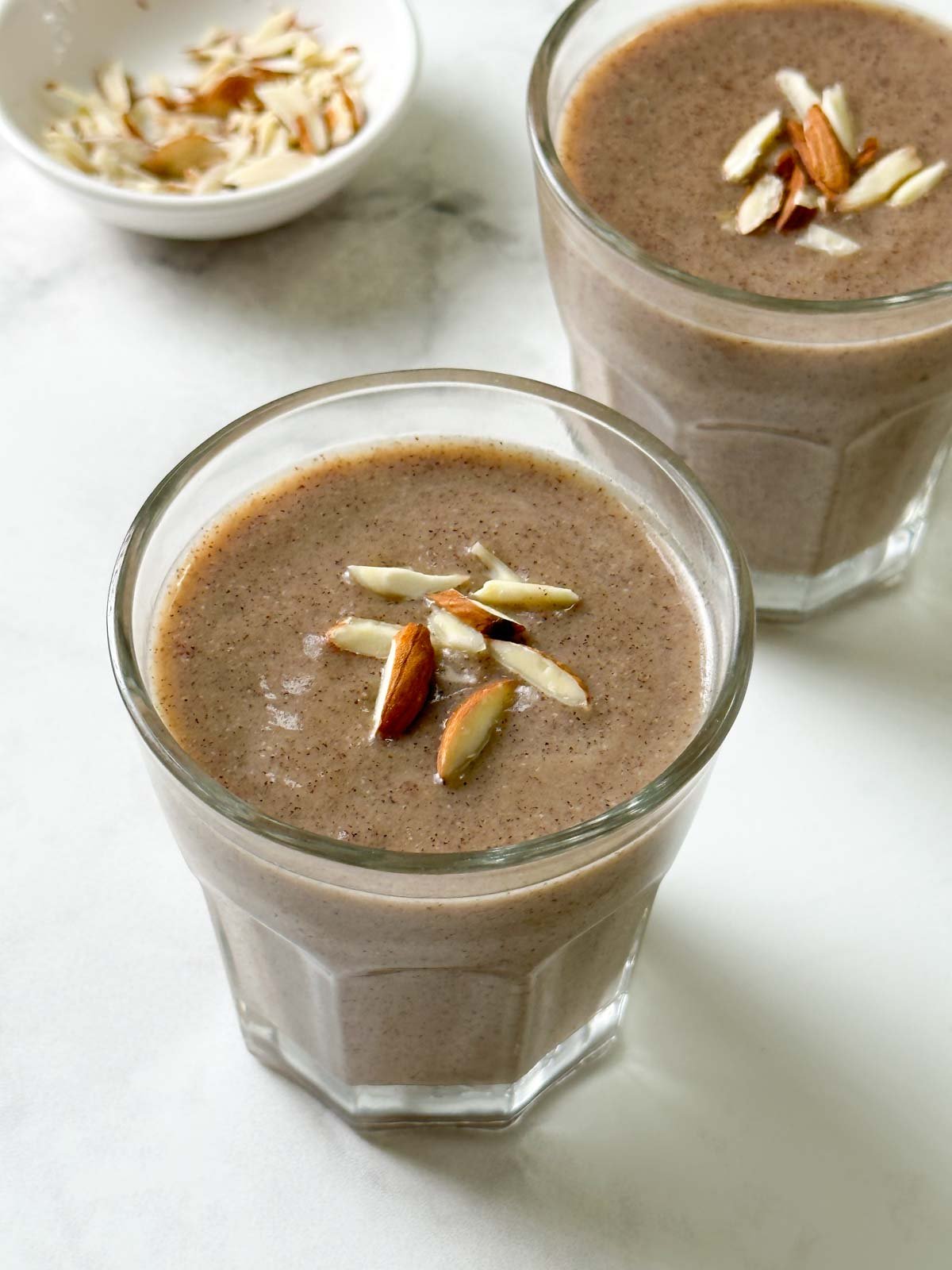ragi malt served in two glass cups garnished with slivered almonds