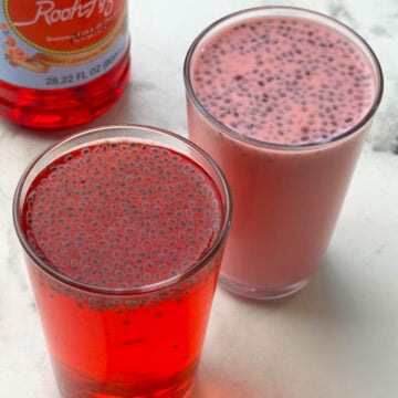 rooh afza drink served in two glasses with rooh afza concentrate bottle on the side.