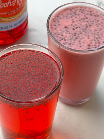 rooh afza drink served in two glasses with rooh afza concentrate bottle on the side.