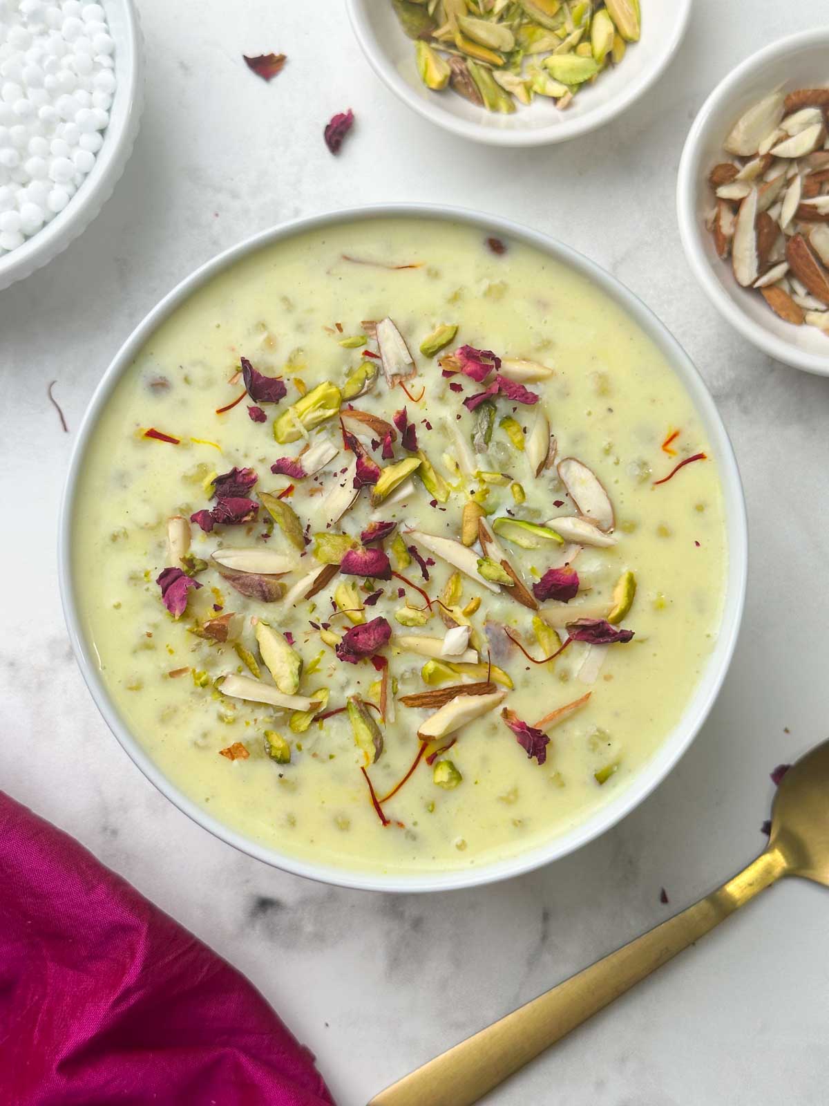 sabudana kheer (indian tapioca pudding) served in a bowl garnished with rose petals and nuts and spoon on the side