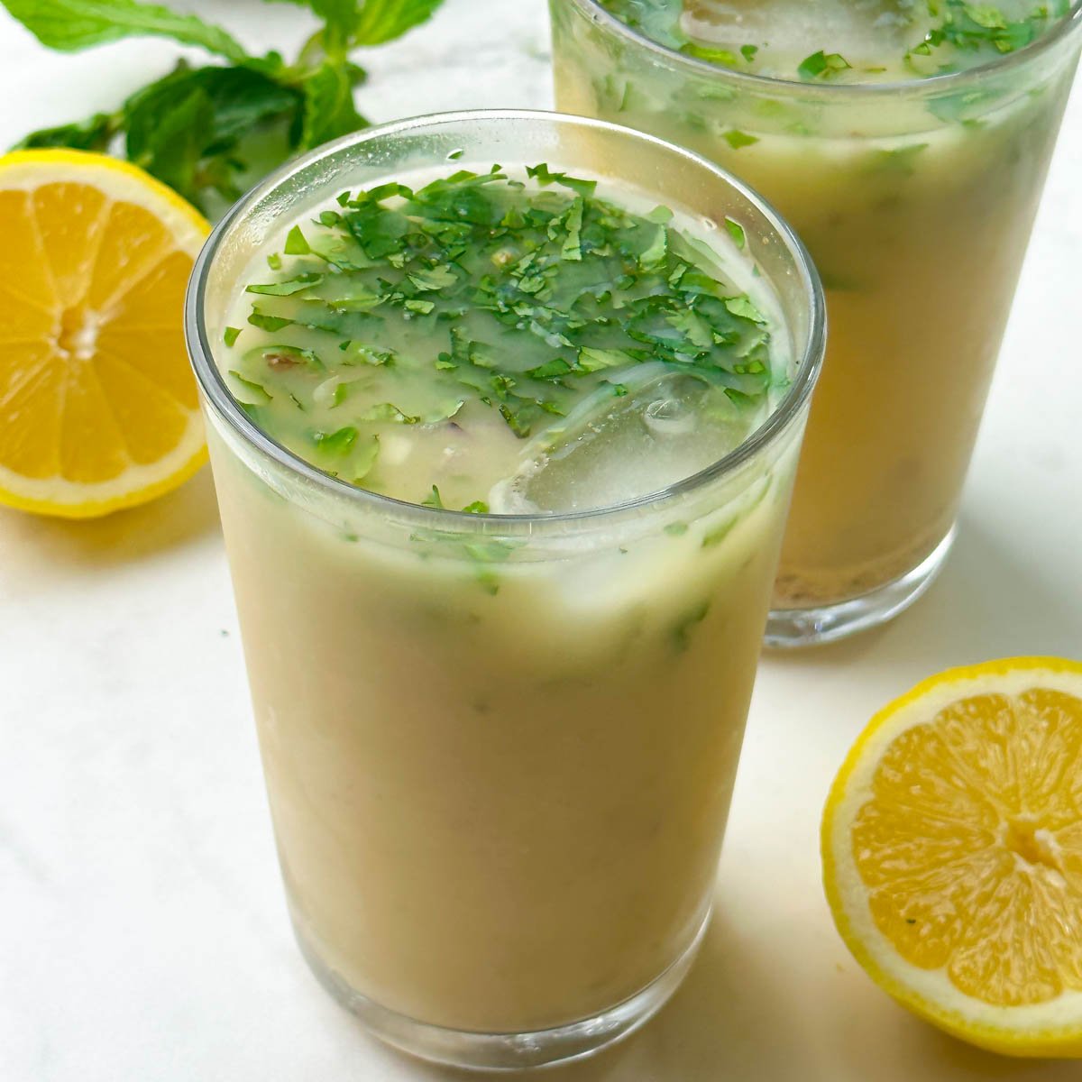 salted sattu sharbat (drink) served in a tall glass garnished with mint and lemon on the side