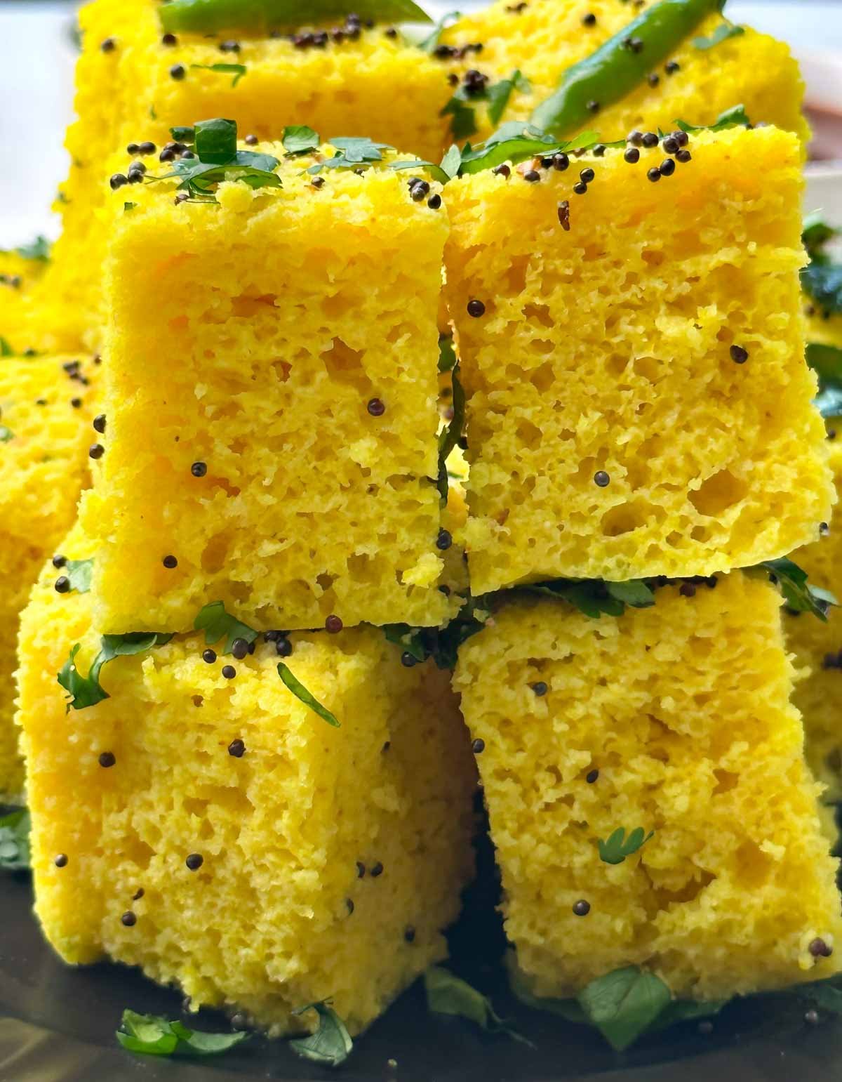 khaman dhokla on a plate with sweet tamarind and green chutney on the side