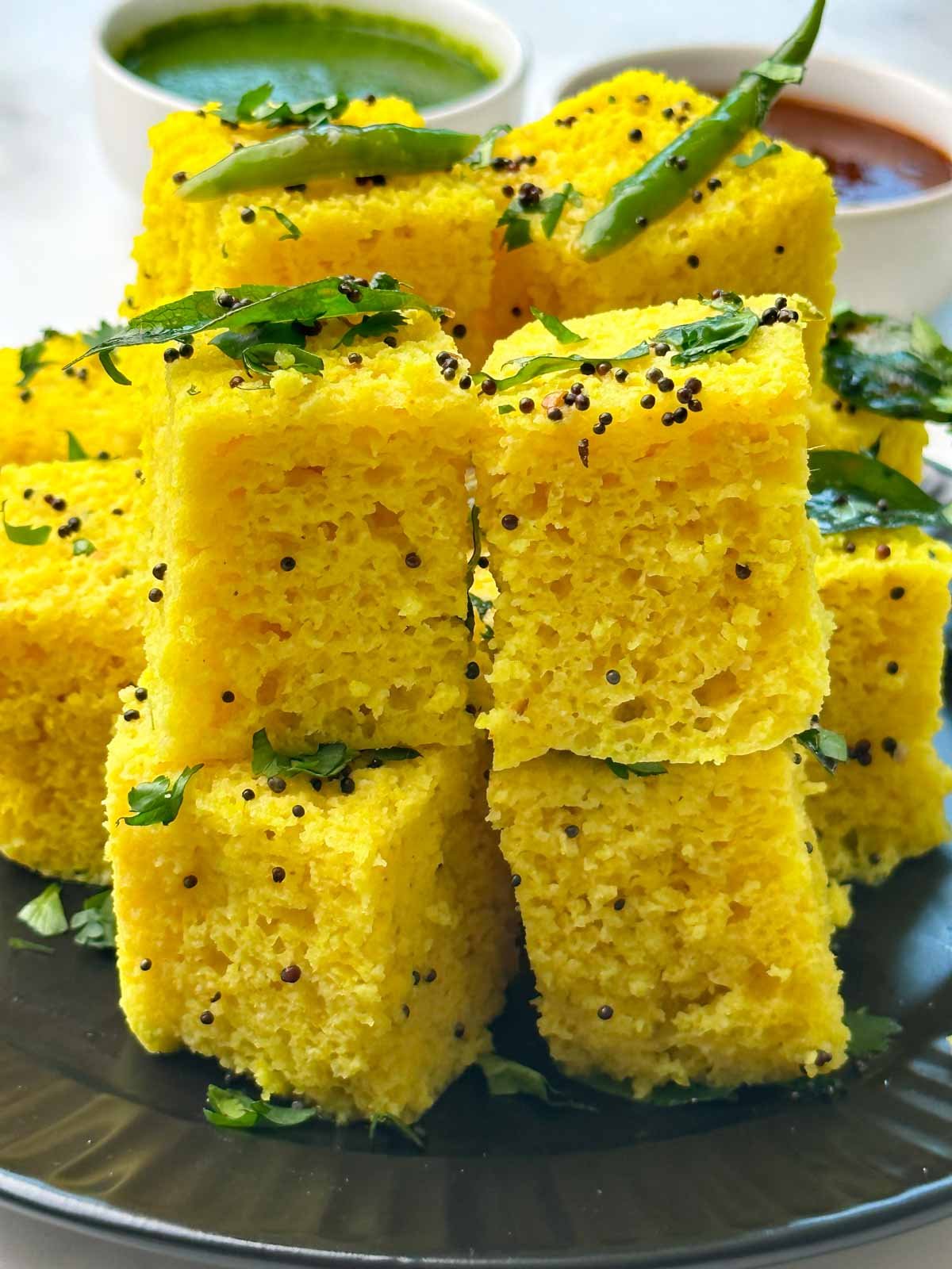 khaman dhokla on a plate with sweet tamarind and green chutney on the side