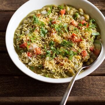 A piping hot masala puri chaat served in a bowl with a spoon.