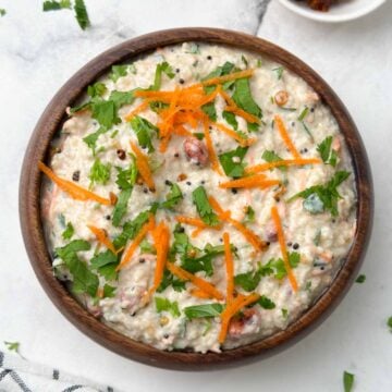 millet curd rice served in a wooden bowl garnished with carrot and coriander leaves with pickle on the side