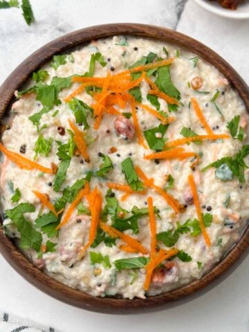 millet curd rice served in a wooden bowl garnished with carrot and coriander leaves with pickle on the side