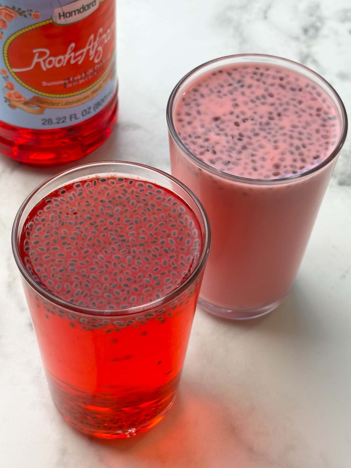 rooh afza milk and rooh afza lemonade served in glasses topped with soaked sabja seed and rooh afza syrup bottle on the side