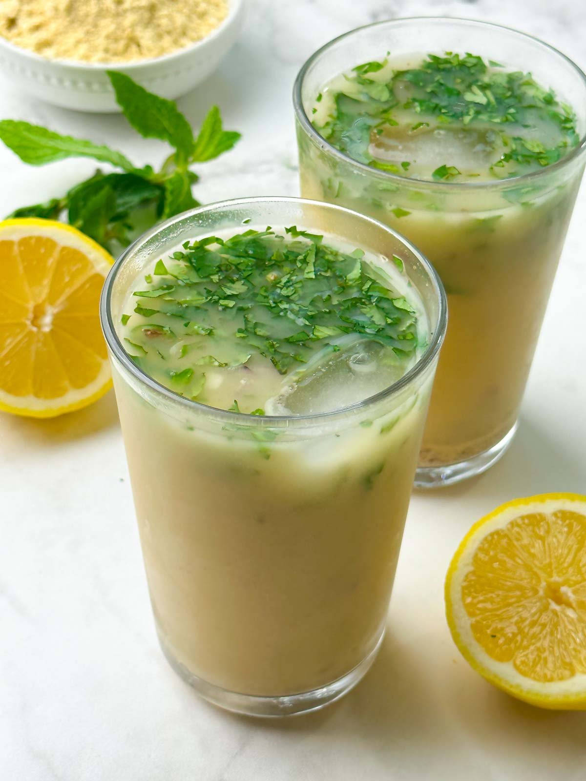 salted roasted chickpea flour beverage served in a tall glass garnished with mint and lemon on the side