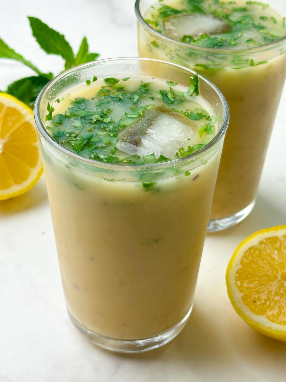 salted sattu sharbat recipe (drink) served in a tall glass garnished with mint and lemon on the side